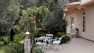 un patio con mesa y sillas en un jardín en Apartments Villa Slavica, en Petrovac na Moru