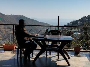 a man sitting at a table with a laptop at kailwood Guest House in McLeod Ganj