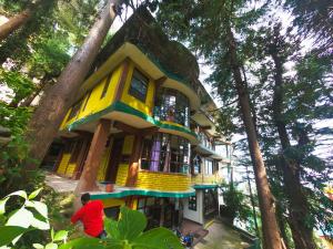 a man standing in front of a tree house at kailwood Guest House in McLeod Ganj