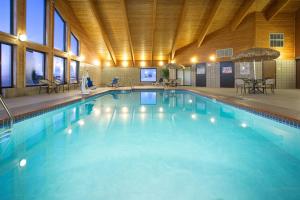 a large swimming pool with blue water in a building at AmericInn by Wyndham New London in New London