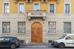 un edificio con una puerta de madera y dos coches aparcados delante en easyhomes - Botta, en Milán