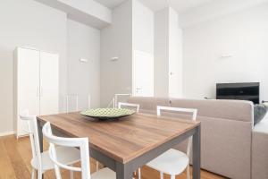 mesa de comedor con sillas blancas y sofá en easyhomes - Botta, en Milán