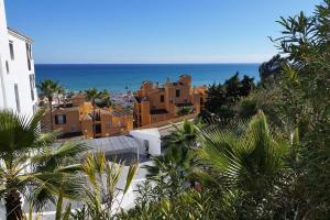 eine Gruppe von Gebäuden auf einem Hügel mit dem Meer in der Unterkunft Blue Suites in Manilva