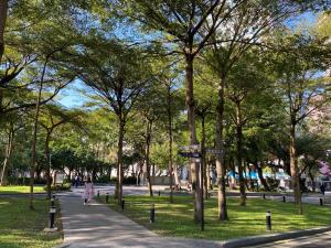 a park with trees and a person walking down a sidewalk at CHECK inn Taipei Main Station in Taipei