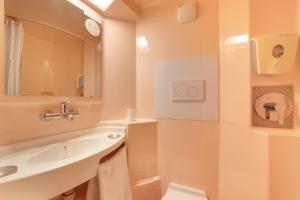 W łazience znajduje się umywalka, toaleta i lustro. w obiekcie Premiere Classe Avignon Parc Des Expositions w mieście Montfavet
