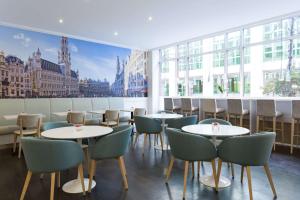 ブリュッセルにあるNH ブリュッセル グランプラス アレンベルグのテーブルと椅子、大きな窓のあるレストラン
