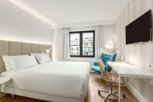 a hotel room with a bed and a desk and a chair at NH Brussels Grand Place Arenberg in Brussels