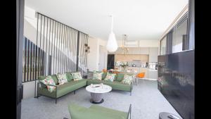 uma sala de estar com sofás verdes e uma mesa em Protaras Elite Pearl Villa Ep17 em Protaras