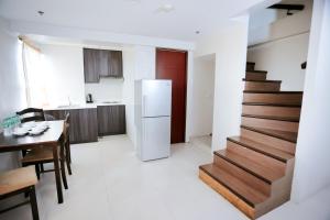 eine Küche mit einer Treppe, einem Tisch und einem Kühlschrank in der Unterkunft Gilmore Tower Suites By SMS Hospitality in Quezon City