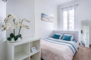a white bedroom with a bed and a vase of flowers at SEA FRONT - Panoramic view with Terraсe - 2BR in Nice