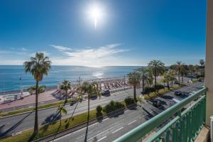 Elle offre une vue sur une rue bordée de palmiers et l'océan. dans l'établissement SEA FRONT - Panoramic view with Terraсe - 2BR, à Nice