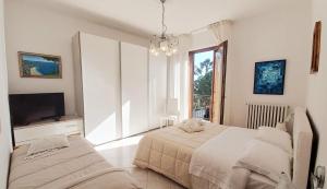 a white bedroom with a bed and a television at Casa Lilly in Porto SantʼElpidio