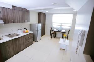 eine Küche mit einer Spüle, einem Kühlschrank und einem Tisch in der Unterkunft Gilmore Tower Suites By SMS Hospitality in Quezon City