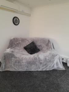 a bed with a blanket on it with a clock on the wall at riverside rooms at wheelgate house in Goole