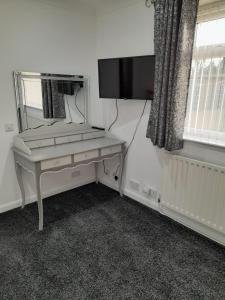 a room with a desk with a mirror and a television at riverside rooms at wheelgate house in Goole