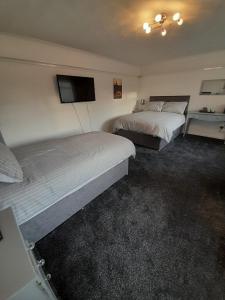 a hotel room with two beds and a flat screen tv at riverside rooms at wheelgate house in Goole