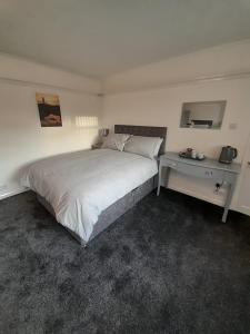 a bedroom with a large bed and a desk at riverside rooms at wheelgate house in Goole