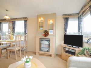 a living room with a television and a dining room at Mountain View Lodge in Holyhead
