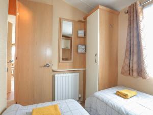 a small bedroom with two beds and a mirror at Mountain View Lodge in Holyhead
