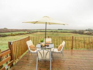 a table and chairs with an umbrella on a deck at Mountain View Lodge in Holyhead