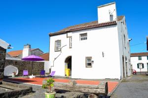 a white building with a purple umbrella and a bench at Casa de Campo, Algarvia in Algarvia