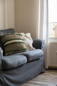 a blue couch sitting in a room with a window at Hoeve de Binnenplaets Schimmert in Schimmert