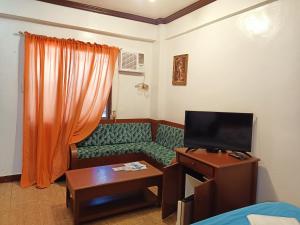 a living room with a couch and a tv at MB's Garden Inn in Mactan