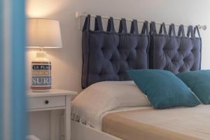 Schlafzimmer mit einem Bett mit blauem Kopfteil und einer Lampe in der Unterkunft Virgilio - Con servizio spiaggia - Narramondo Villas in Tortoreto Lido