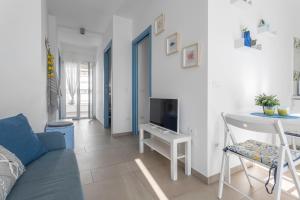 ein Wohnzimmer mit einem blauen Sofa und einem TV in der Unterkunft Virgilio - Con servizio spiaggia - Narramondo Villas in Tortoreto Lido