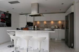 a kitchen with white cabinets and bar stools at The White House Beach Villa in Rafina