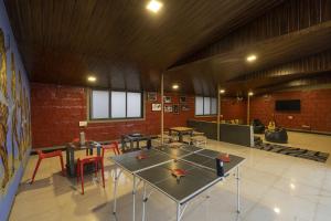 a room with tables and chairs and a ping pong table at Zostel Kolad in Kolād