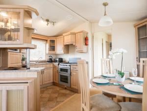 a kitchen with wooden cabinets and a table with chairs at Mountain View Lodge 2 in Holyhead