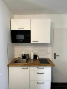 uma cozinha com armários brancos, um lavatório e um micro-ondas em Schöne Wohnung nahe Köln em Colônia