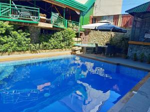 a swimming pool with blue water and an umbrella at MB's Garden Inn in Mactan