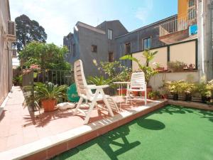 two chairs and a table on a patio with green grass at Piccadilly House in Catania