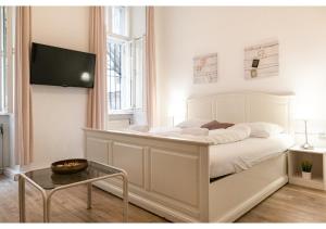 sypialnia z dużym białym łóżkiem i telewizorem z płaskim ekranem w obiekcie Stylish Apt - Ideal for Longstays near Matzleinsdorferplatz w Wiedniu