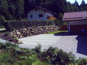a garden with a stone wall and a house at Ferienwohnung Reisinger in Arnbruck