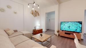 ein Wohnzimmer mit einem Sofa und einem Flachbild-TV in der Unterkunft Le Beau Bourg *** in Straßburg