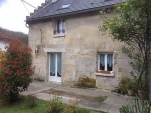 Casa de piedra con puerta blanca y 2 ventanas en chez tatie yvette, en Cuise-la-Motte