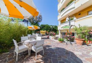 卡托利卡的住宿－Residence Promenade，庭院配有桌椅和遮阳伞。