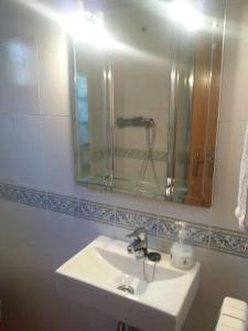ein weißes Badezimmer mit einem Waschbecken und einem Spiegel in der Unterkunft Adosado gran terraza parking bodega ideal bicis in Villanova