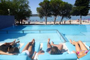 a group of people laying in a swimming pool at a beach at Hotel Adriatic in Biograd na Moru