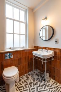 een badkamer met een toilet, een wastafel en een spiegel bij The Pride of Paddington in Londen
