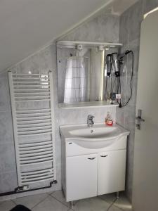 La salle de bains est pourvue d'un lavabo blanc et d'un miroir. dans l'établissement Panorama Apartman, à Molvice