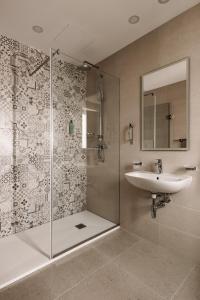 een badkamer met een douche, een wastafel en een spiegel bij Urban Isle Hotel in Il-Gżira