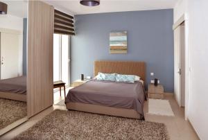 a bedroom with blue walls and a bed and a mirror at Valley of Honey Apartment in Mosta