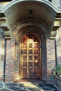 una puerta de madera en un edificio de ladrillo con un arco en The Sleeping Bao B&B, en Pietermaritzburg