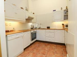 Una cocina con gabinetes blancos y piso de baldosas. en Val's Seaview, en Ilfracombe 9 fotos más