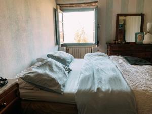 Casale gli ulivi في Donnini: سرير غير مرتب في غرفة نوم مع نافذة