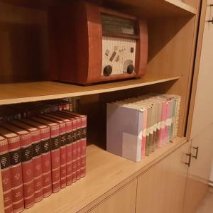 a shelf with books and a clock on it at Miklavževa hiša with a bread oven in Železniki